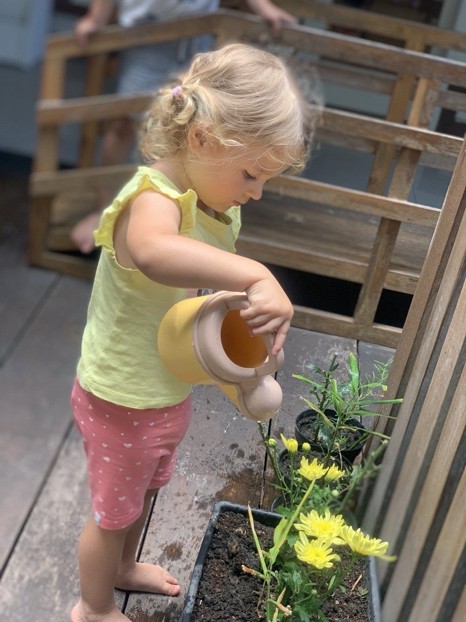 A child watering flowers in the garden beds at Balu Kids